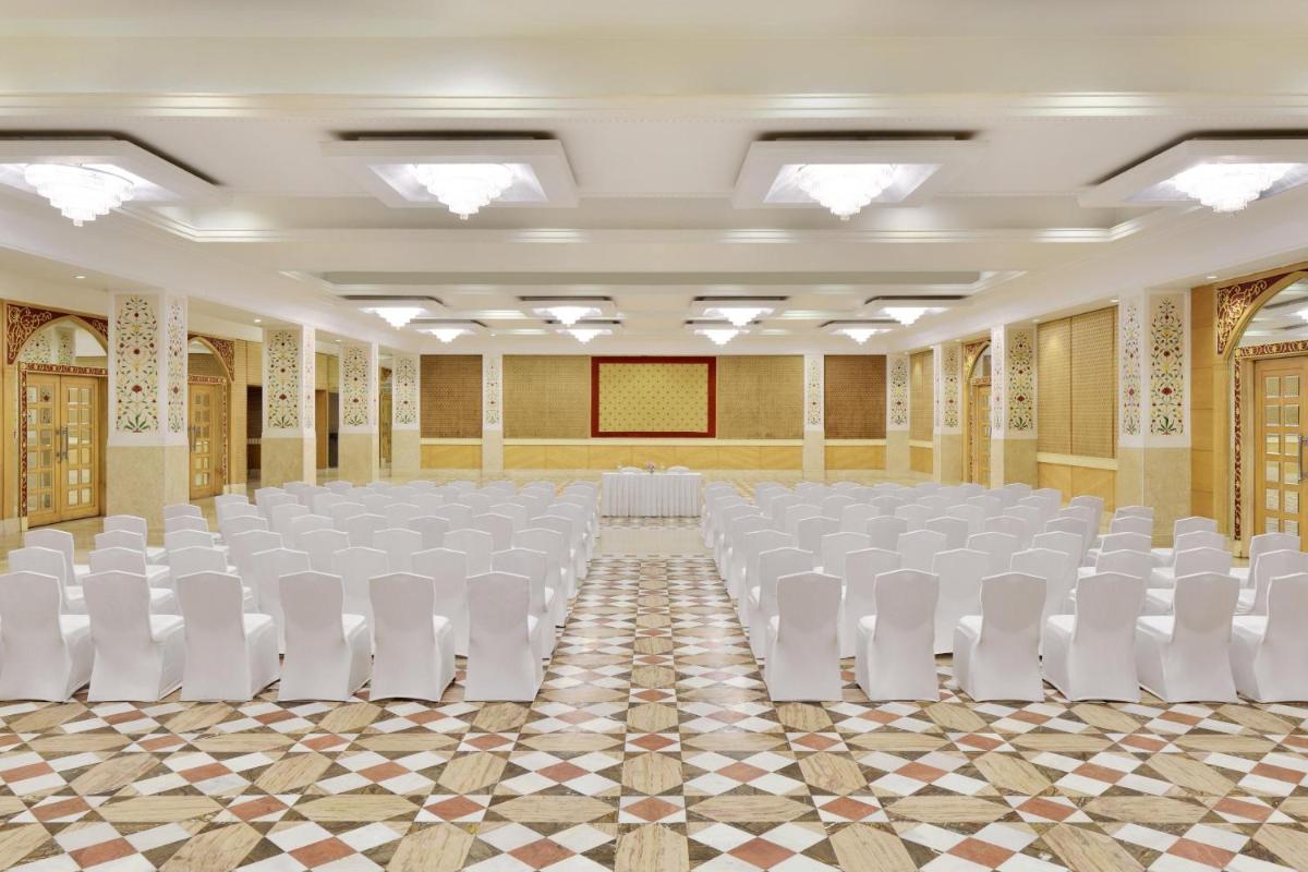 an empty banquet hall with white chairs and a stage at Le Meridien Jaipur Resort & Spa in Jaipur
