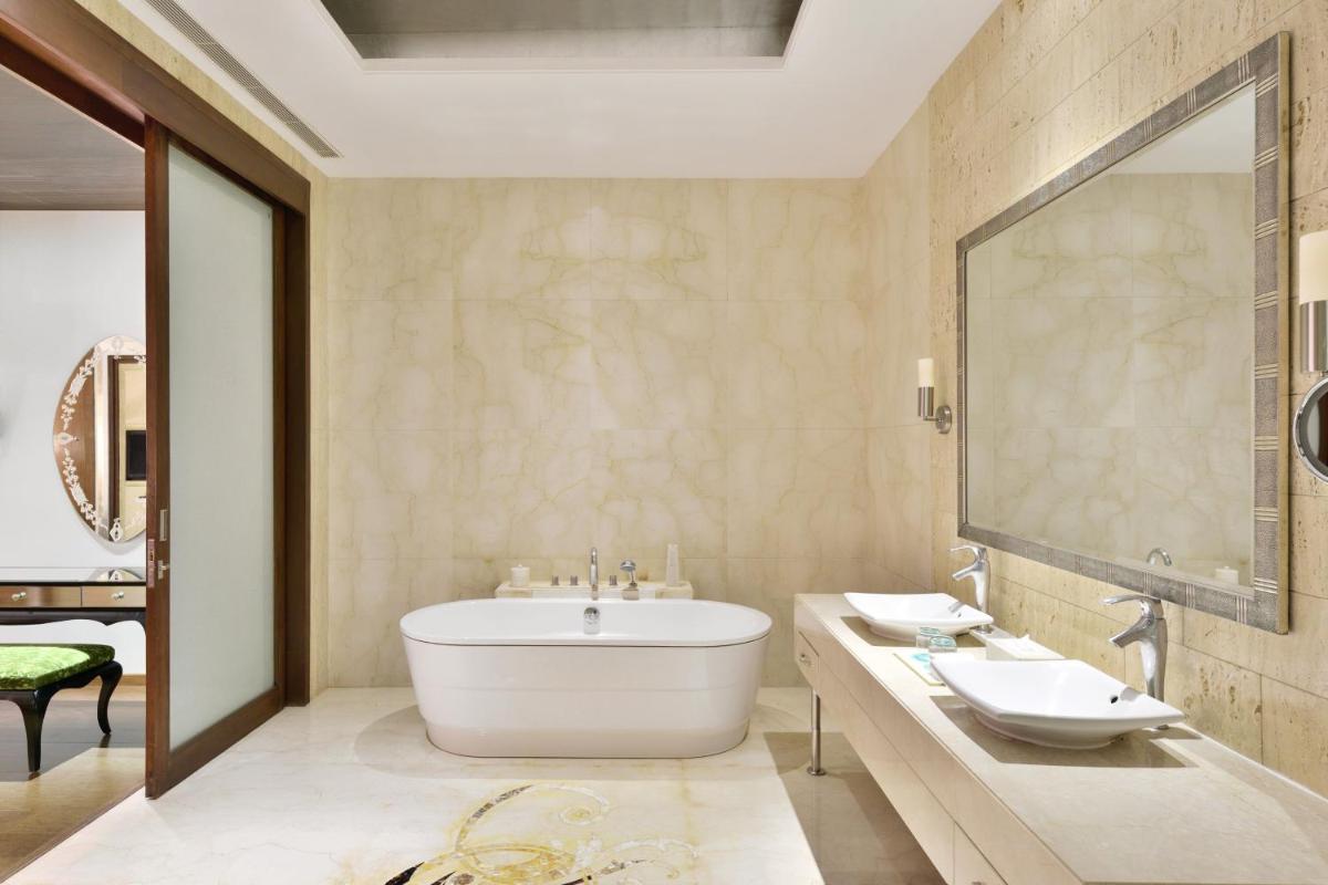 a bathroom with a tub and two sinks and a mirror at Le Meridien Jaipur Resort & Spa in Jaipur