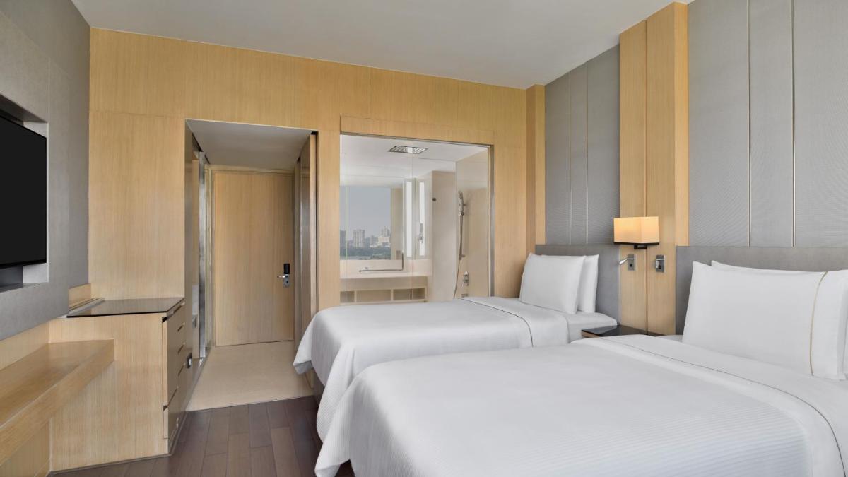 a hotel room with two beds and a television at The Westin Mumbai Powai Lake in Mumbai