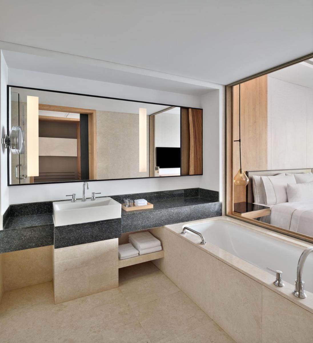 a bathroom with a tub and a sink and a bed at The Westin Mumbai Powai Lake in Mumbai