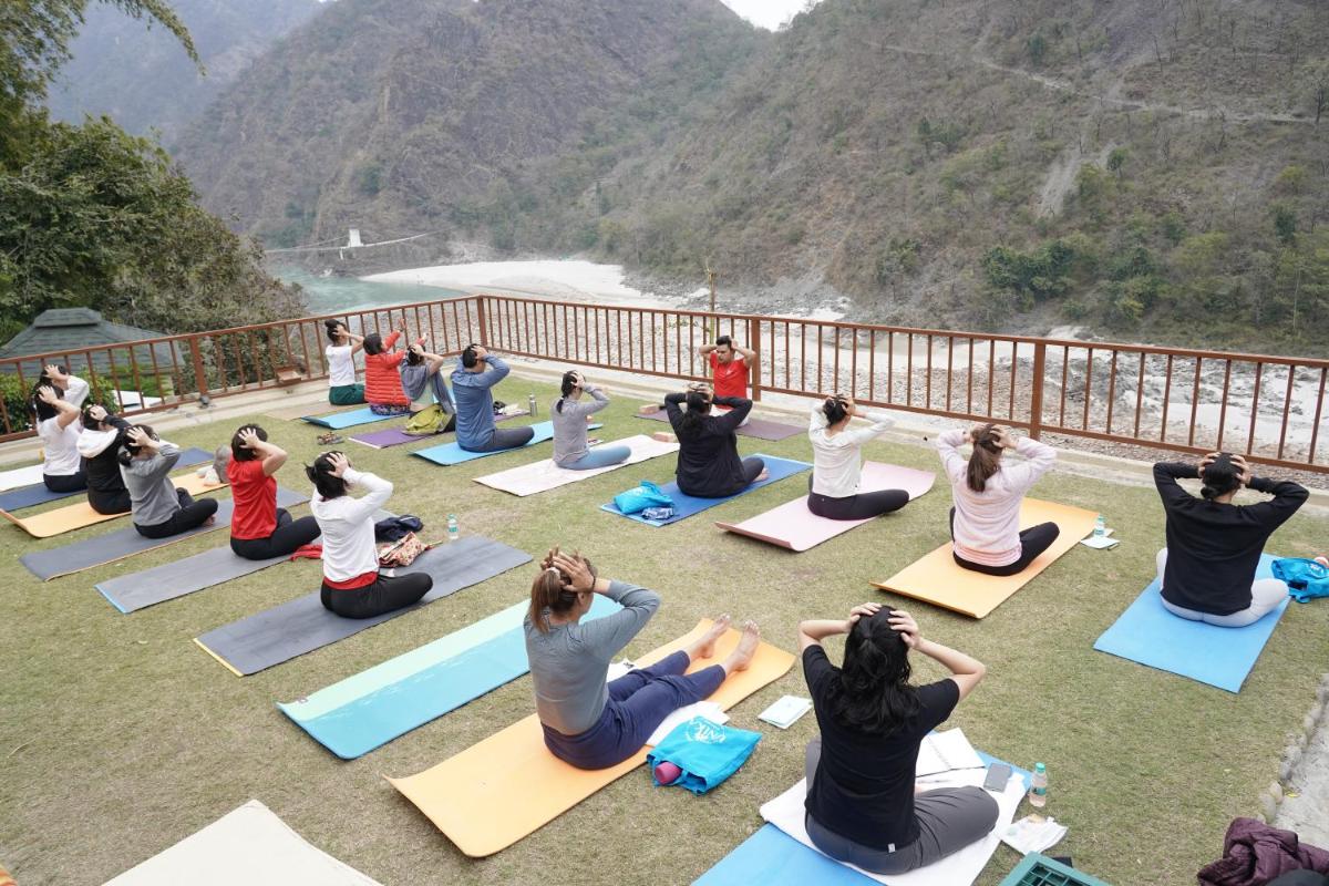 a group of people sitting in a yoga pose on a deck at Raga on the Ganges, Rishikesh in Rishīkesh
