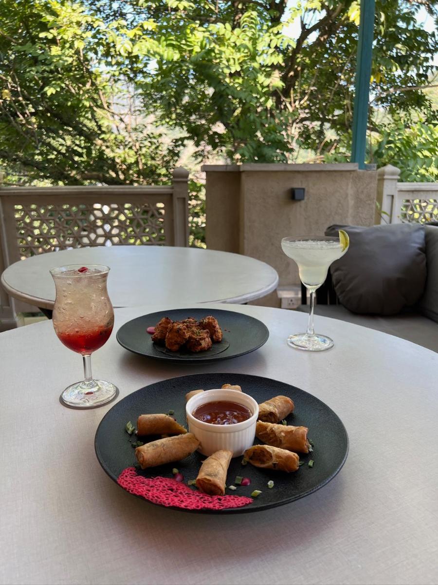 a table with two plates of food and two wine glasses at Raga on the Ganges, Rishikesh in Rishīkesh