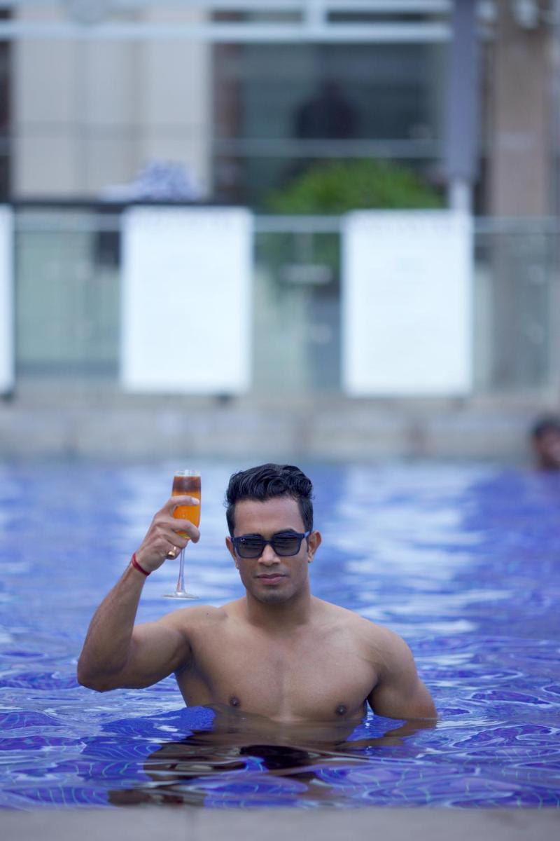 a man holding a glass of wine in a swimming pool at Novotel Hyderabad Airport in Hyderabad