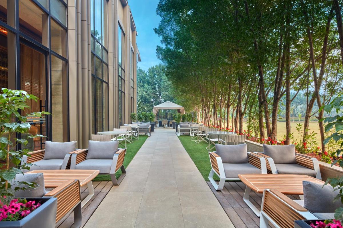 a row of chairs and tables on a sidewalk next to a building at Hilton Gurugram Baani City Centre in Gurgaon