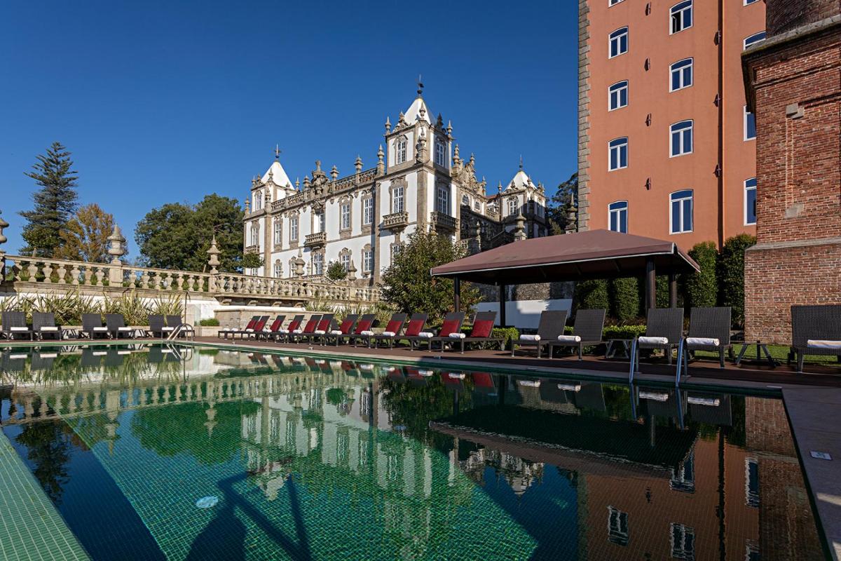uma piscina com cadeiras e um prédio ao fundo em Pestana Palacio do Freixo, Pousada & National Monument - The Leading Hotels of the World no Porto