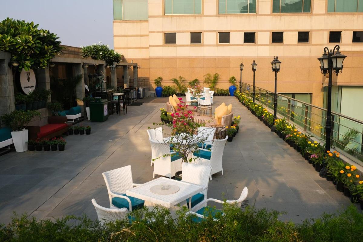 a patio with white tables and chairs and a building at Crowne Plaza Today Gurugram by IHG in Gurgaon