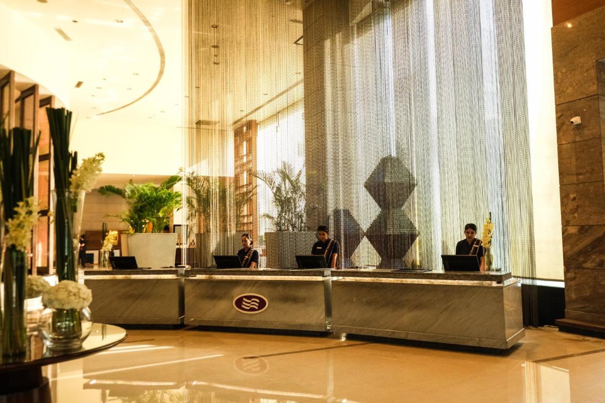 a lobby with three men sitting at laptops in a building at Crowne Plaza Today Gurugram by IHG in Gurgaon