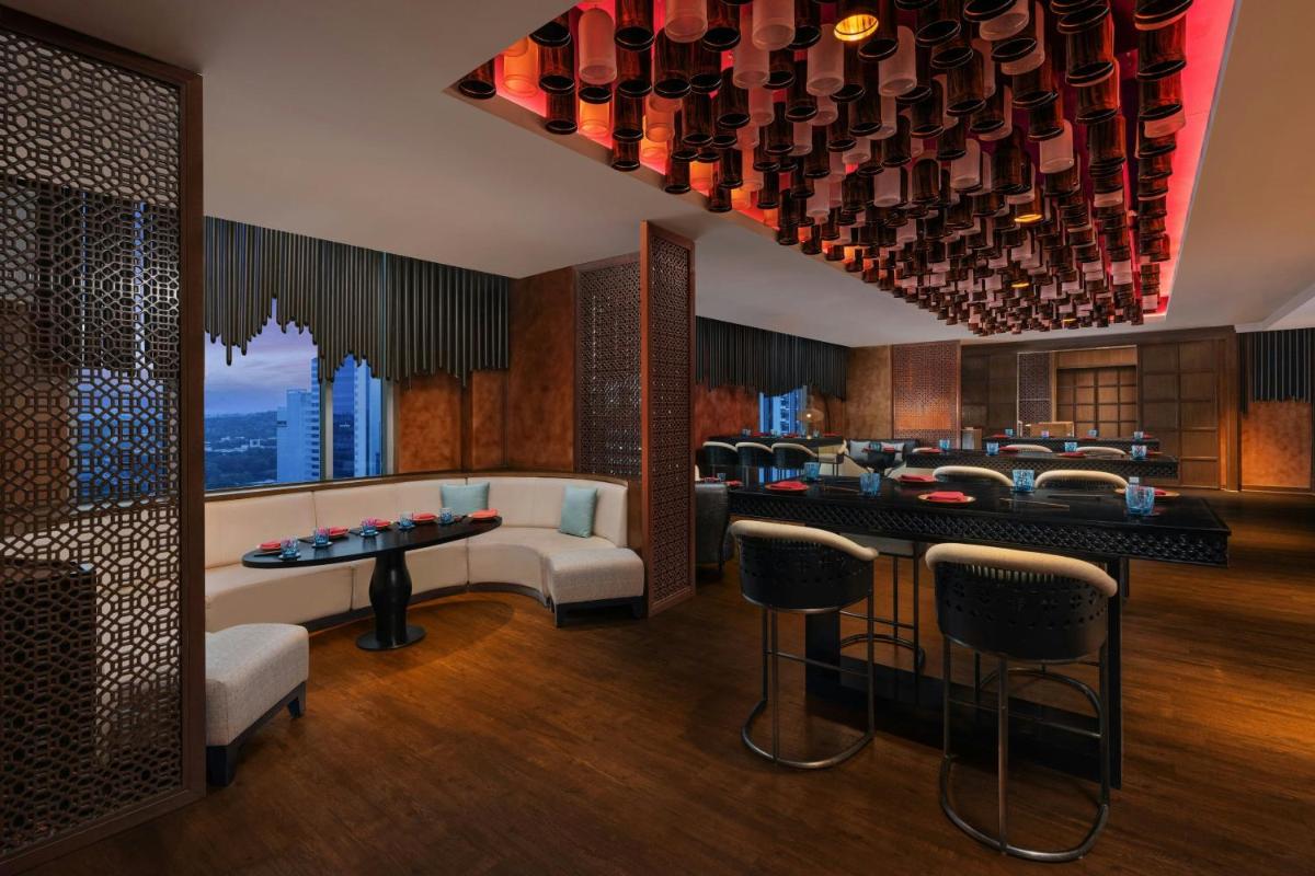 a room with a bar with chairs and a table at Sheraton Hyderabad Hotel in Hyderabad