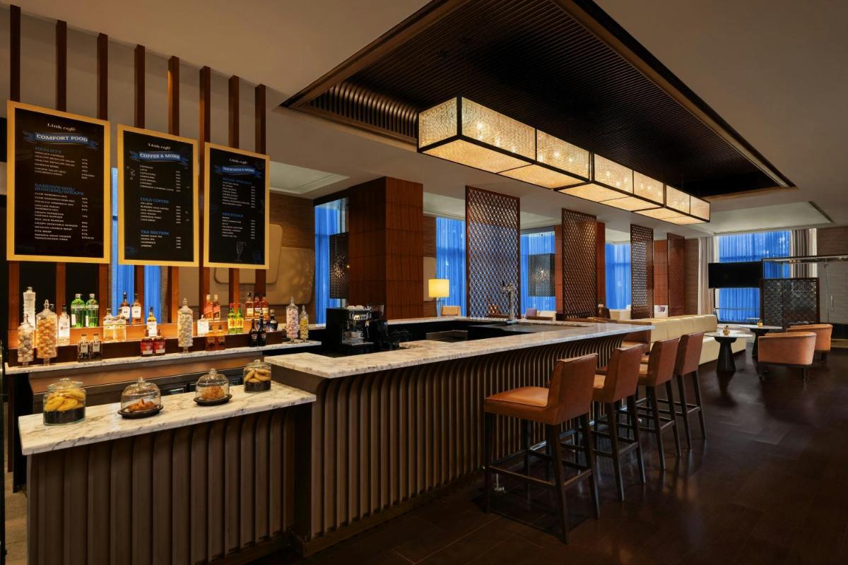 a bar in a hotel with chairs and a counter at Sheraton Hyderabad Hotel in Hyderabad