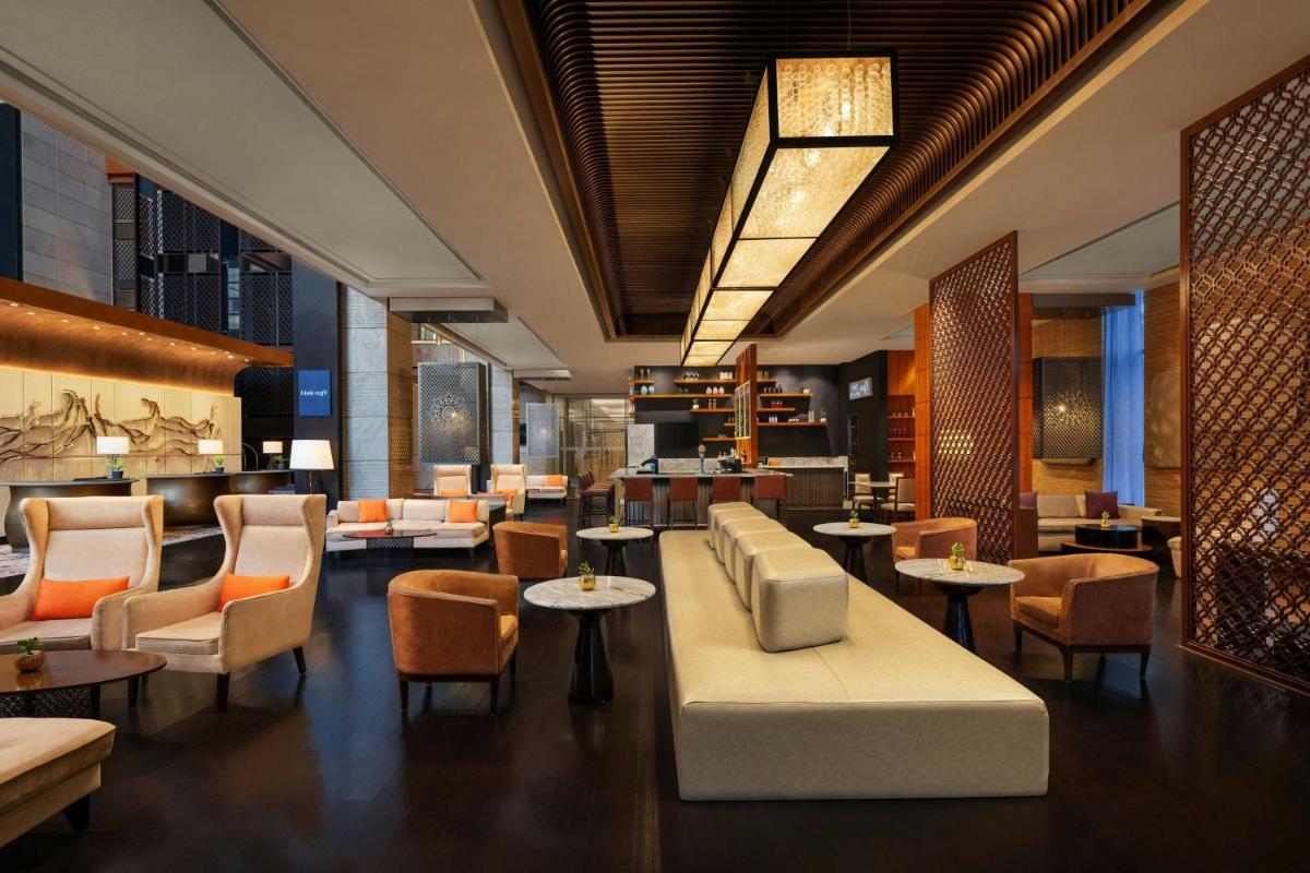 a lobby of a hotel with tables and chairs at Sheraton Hyderabad Hotel in Hyderabad