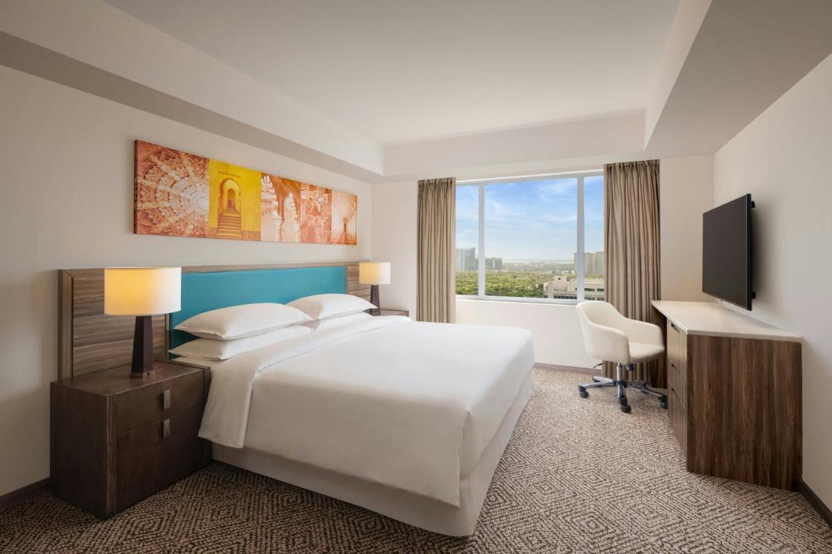a hotel room with a bed and a desk and a window at Sheraton Hyderabad Hotel in Hyderabad