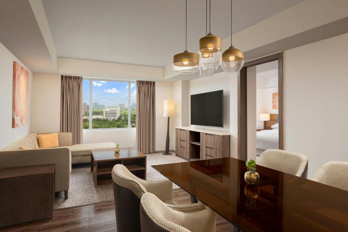 a living room with a couch and a table and a television at Sheraton Hyderabad Hotel in Hyderabad
