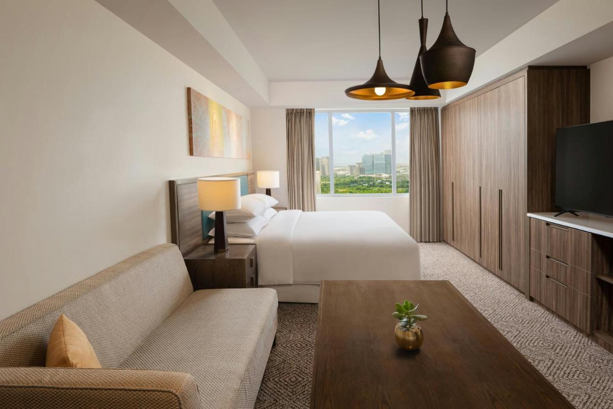 a hotel room with a bed and a couch and a tv at Sheraton Hyderabad Hotel in Hyderabad