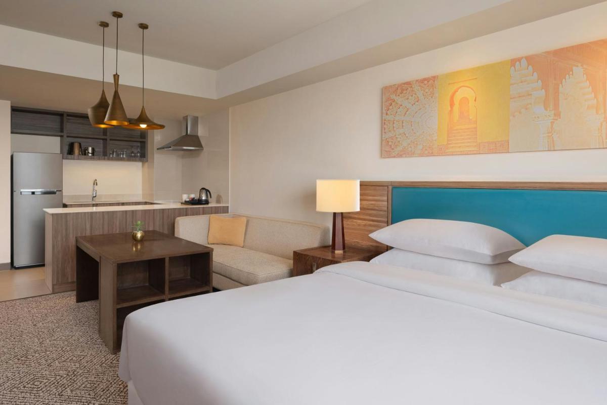 a bedroom with a large bed and a kitchen at Sheraton Hyderabad Hotel in Hyderabad