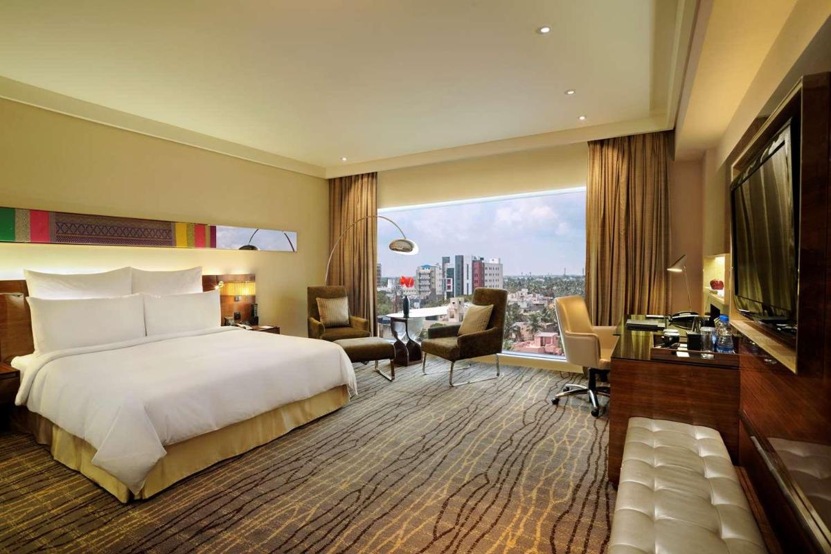 a hotel room with a bed and a large window at Hilton Chennai in Chennai