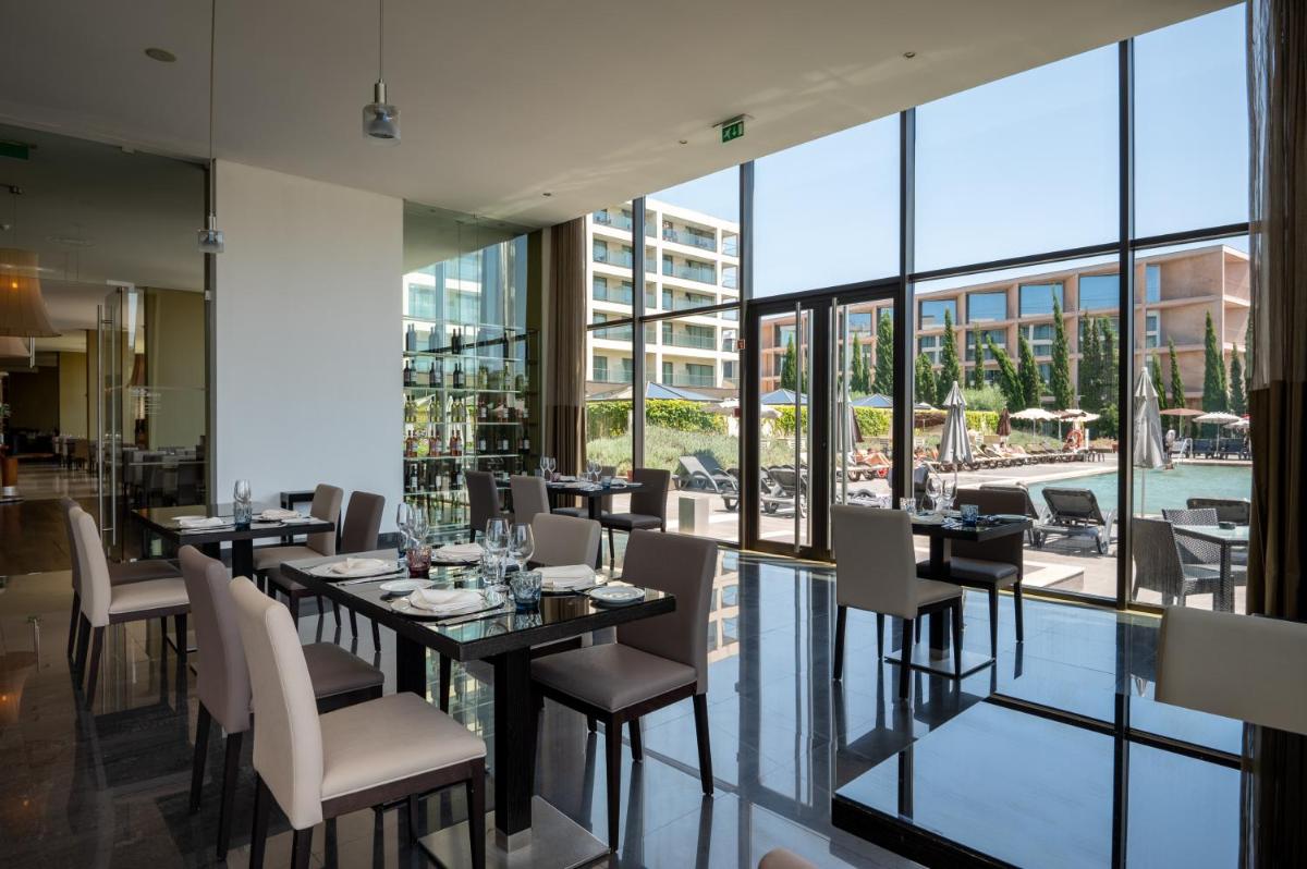 um restaurante com mesas e cadeiras e uma grande janela em Vila Gale Coimbra em Coimbra