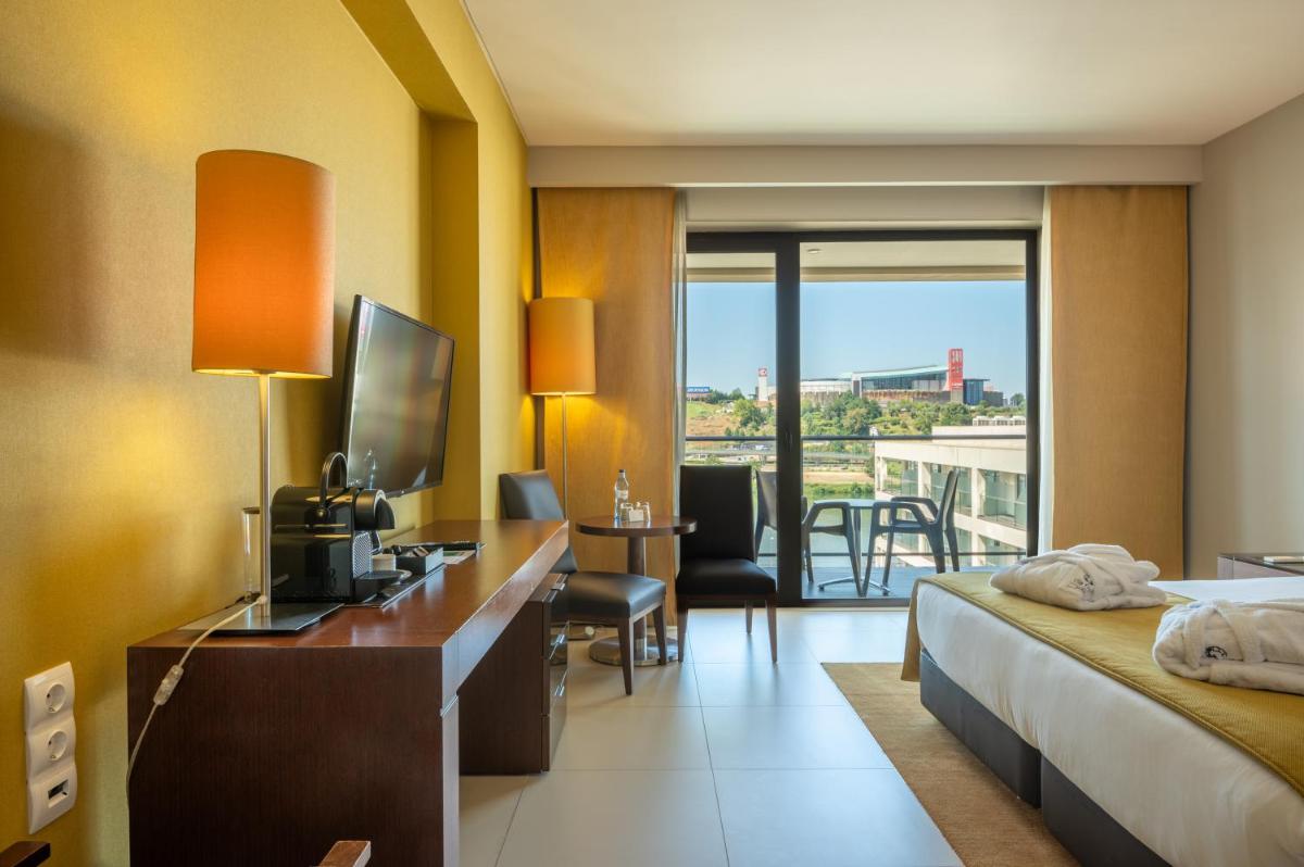 um quarto de hotel com uma cama e uma escrivaninha com uma televisão em Vila Gale Coimbra em Coimbra