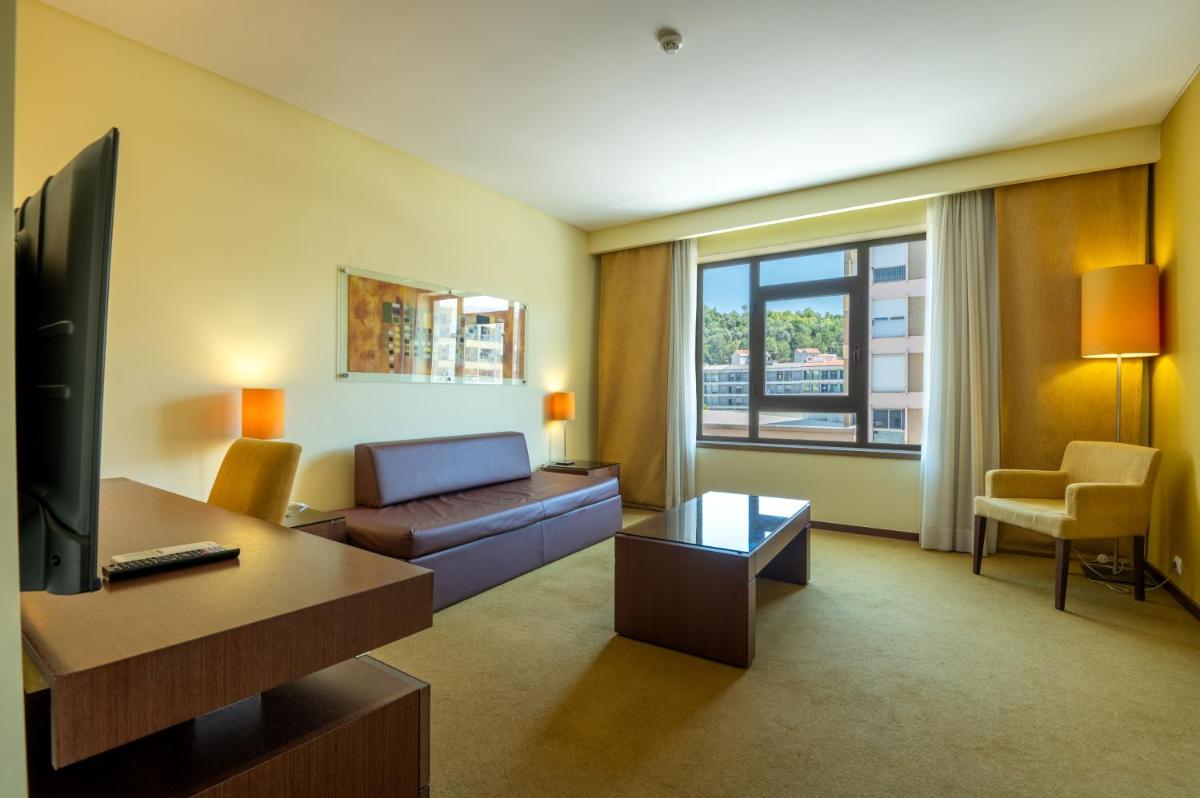 uma sala de estar com um sofá e uma TV em Vila Gale Coimbra em Coimbra