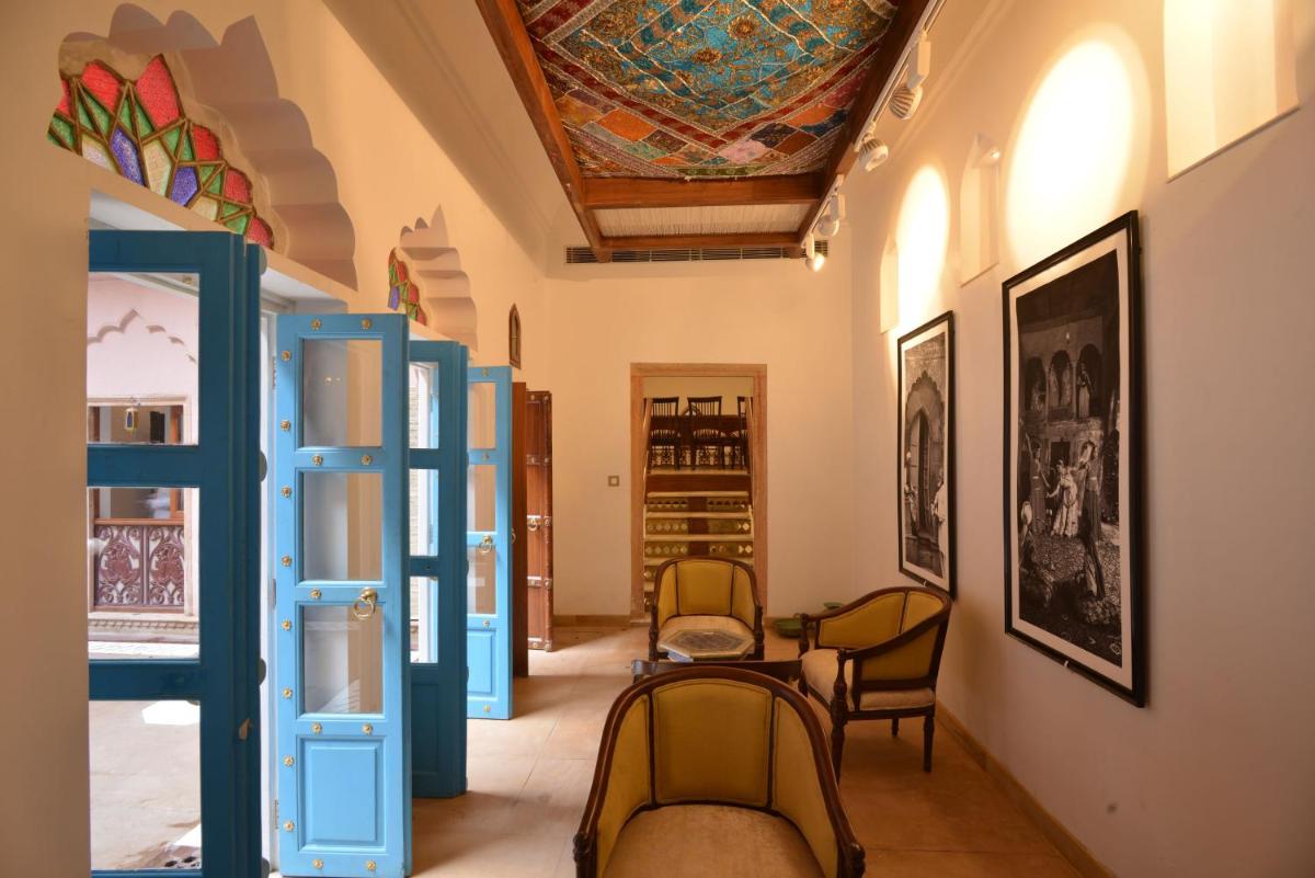 a room with chairs and a ceiling with a painting at Haveli Dharampura & Golden Haveli- UNESCO awarded Boutique Heritage Hotel in New Delhi a room with chairs and a ceiling with a painting at Haveli Dharampura & Golden Haveli- UNESCO awarded Boutique Heritage Hotel in New Delhi