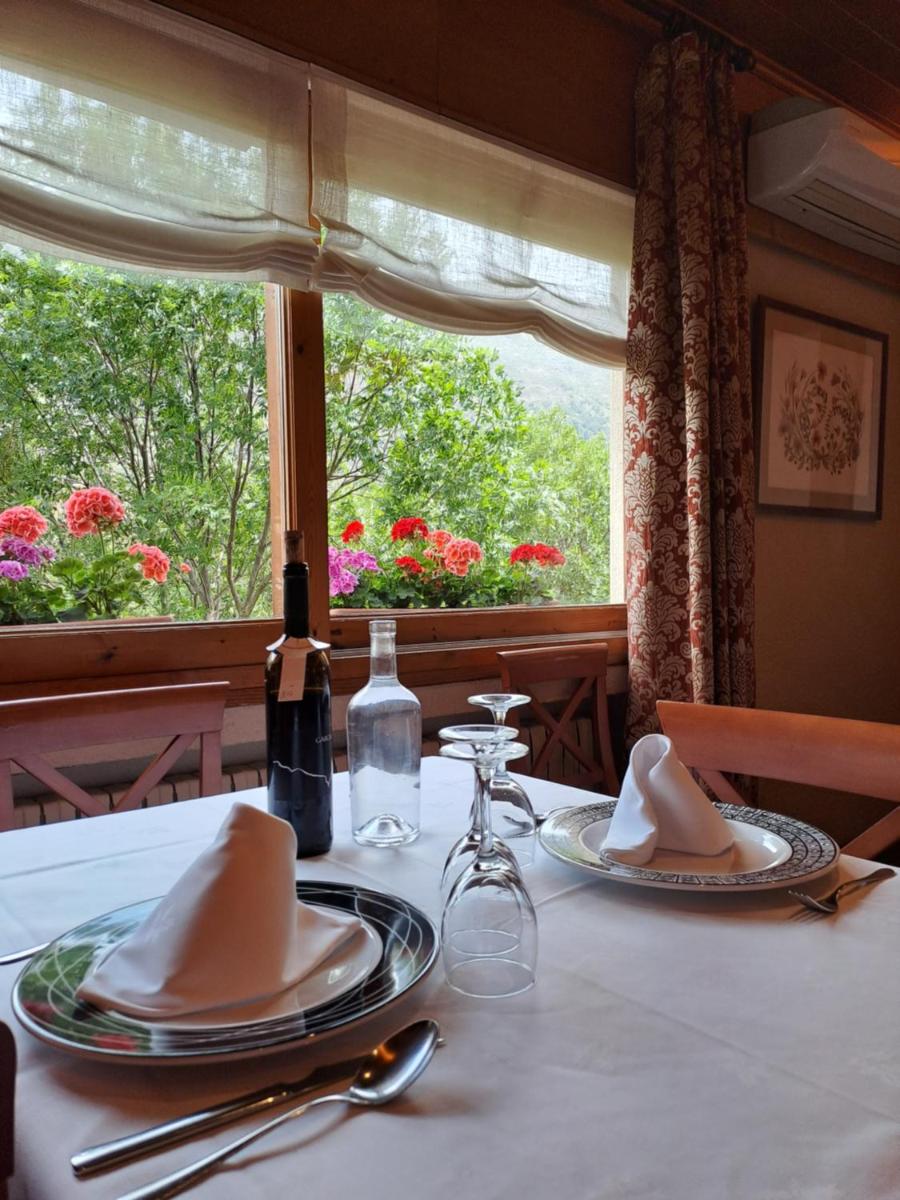 una mesa con platos y servilletas y una ventana con flores en Hotel La Morera, en Valencia de Aneu