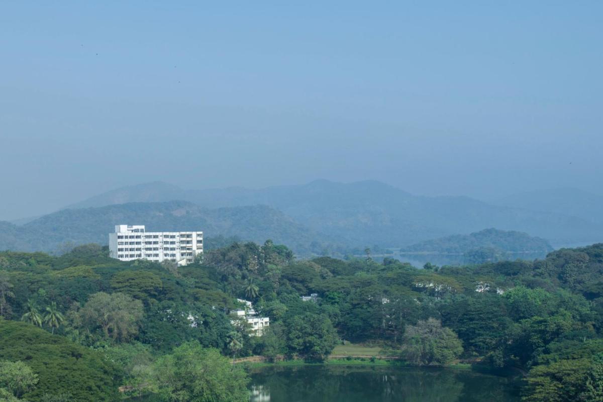 a large white building in the middle of a forest at The Westin Mumbai Powai Lake in Mumbai