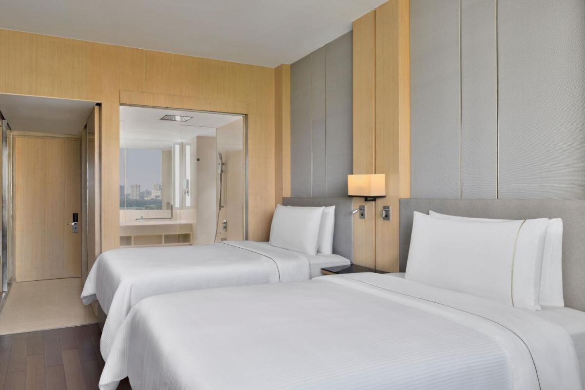 two beds in a hotel room with white sheets at The Westin Mumbai Powai Lake in Mumbai
