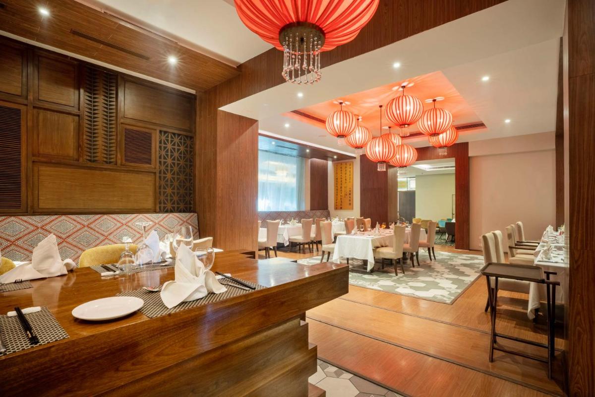 a dining room with tables and chairs and chandeliers at Radisson Hyderabad Hitec City in Hyderabad