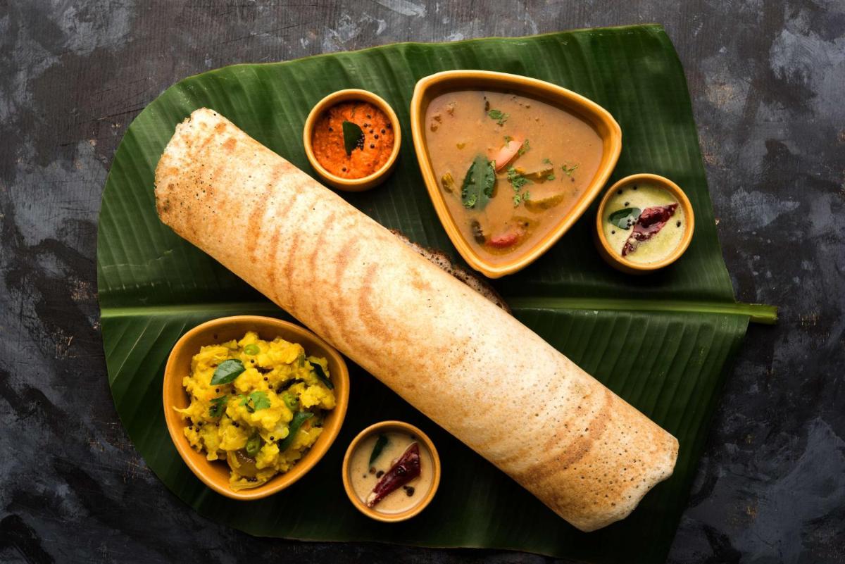 a plate of food with a burrito and soup on a banana leaf at Radisson Jaipur City Center in Jaipur