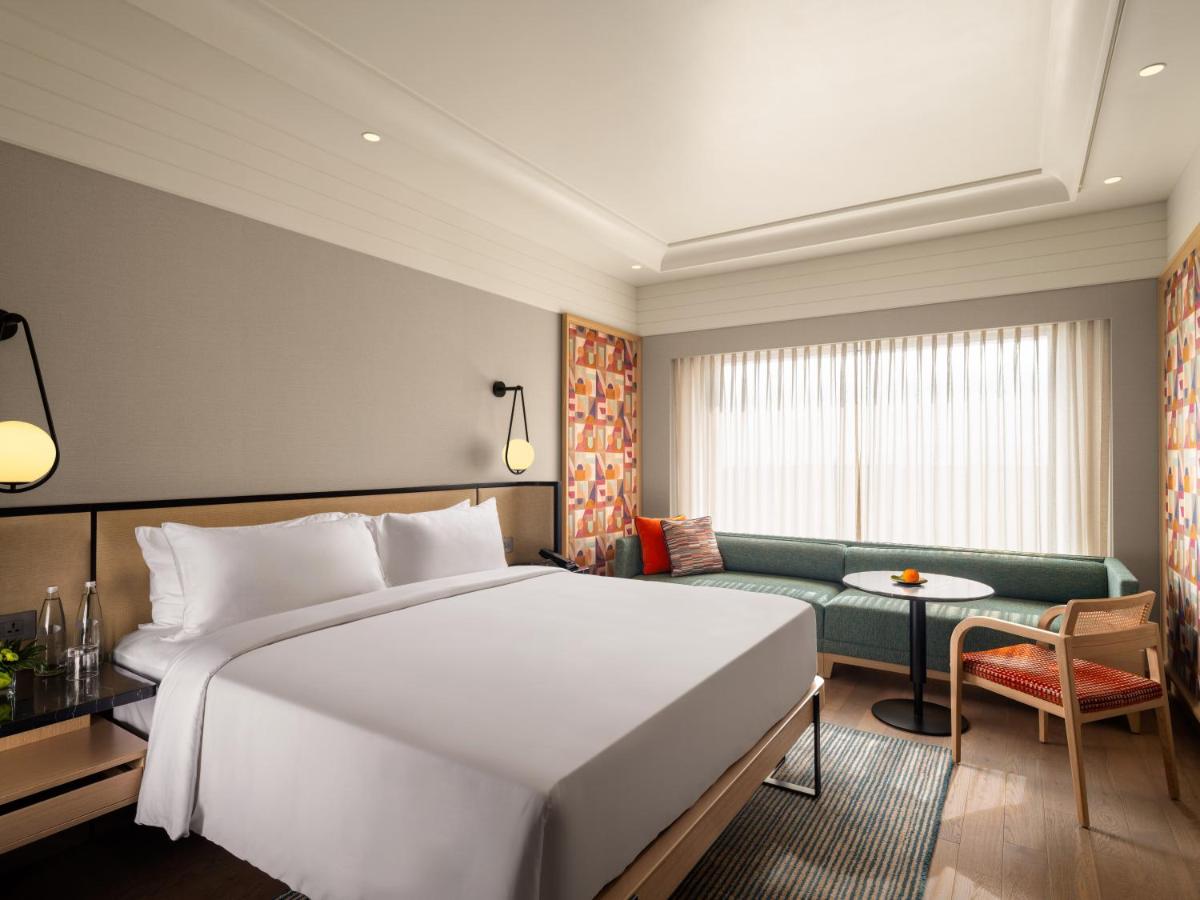 a bedroom with a large white bed and a couch at Pullman Chennai Anna Salai - Premium Brand By Accor in Chennai