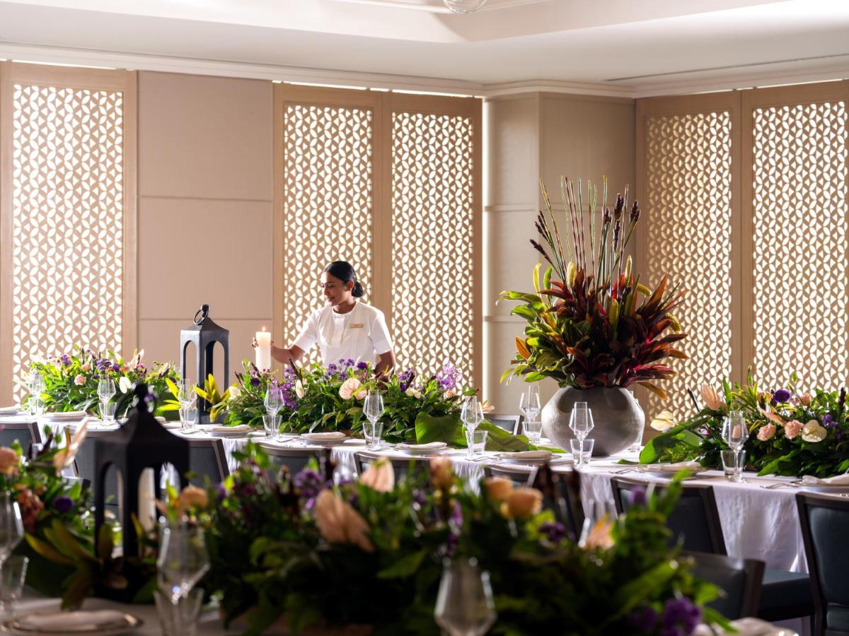 a woman standing in front of a table with flowers at Pullman Chennai Anna Salai - Premium Brand By Accor in Chennai