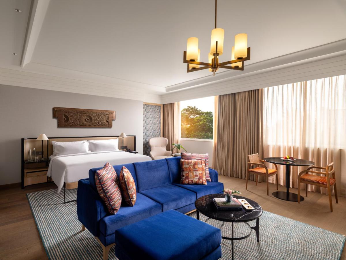 a hotel room with a bed and a blue couch at Pullman Chennai Anna Salai - Premium Brand By Accor in Chennai