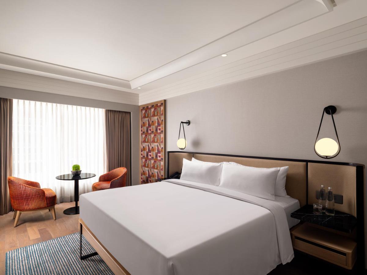 a bedroom with a large white bed and a table at Pullman Chennai Anna Salai - Premium Brand By Accor in Chennai