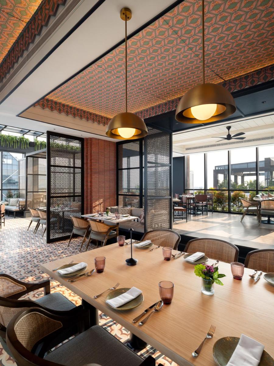 a restaurant with wooden tables and chairs and windows at Pullman Chennai Anna Salai - Premium Brand By Accor in Chennai