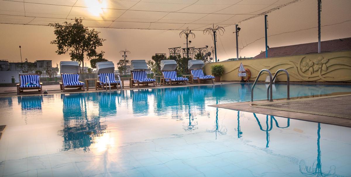 a swimming pool with blue chairs in a building at The Orchid Hotel Mumbai Vile Parle in Mumbai
