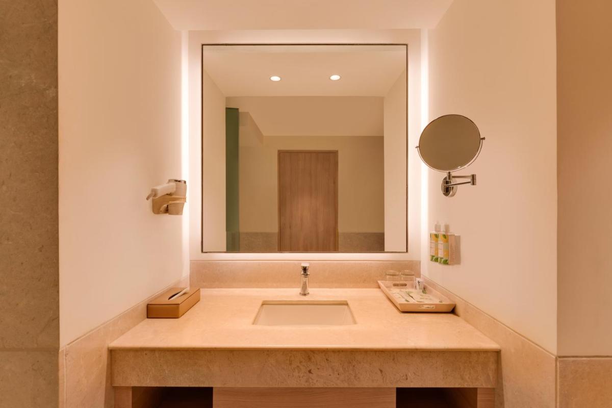 a bathroom with a sink with a large mirror at Lemon Tree Premier Hitec City Hyderabad in Hyderabad