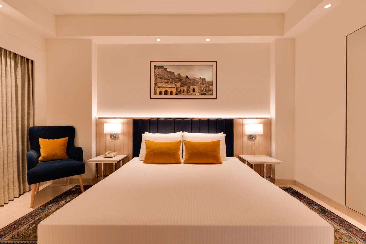 a bedroom with a large bed and a chair at Lemon Tree Premier Hitec City Hyderabad in Hyderabad