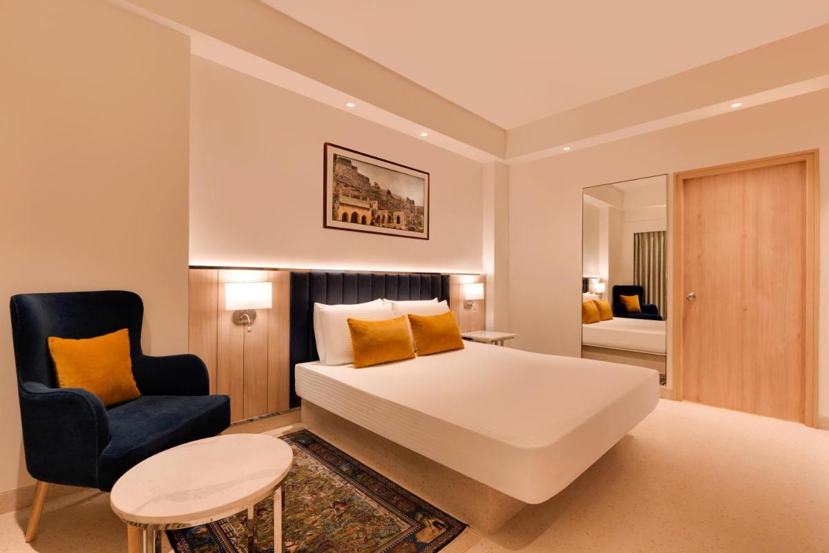 a bedroom with a white bed and a blue chair at Lemon Tree Premier Hitec City Hyderabad in Hyderabad