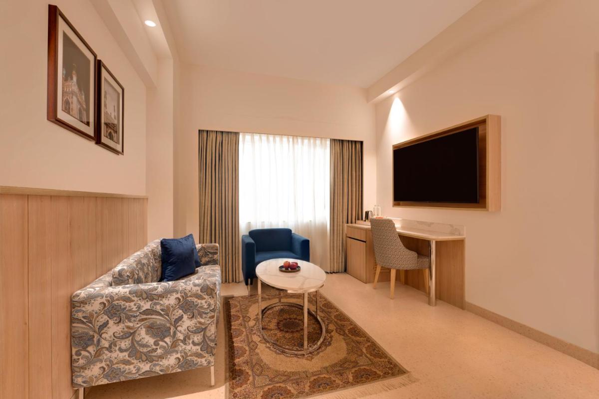 a hotel room with a couch and a table and a television at Lemon Tree Premier Hitec City Hyderabad in Hyderabad