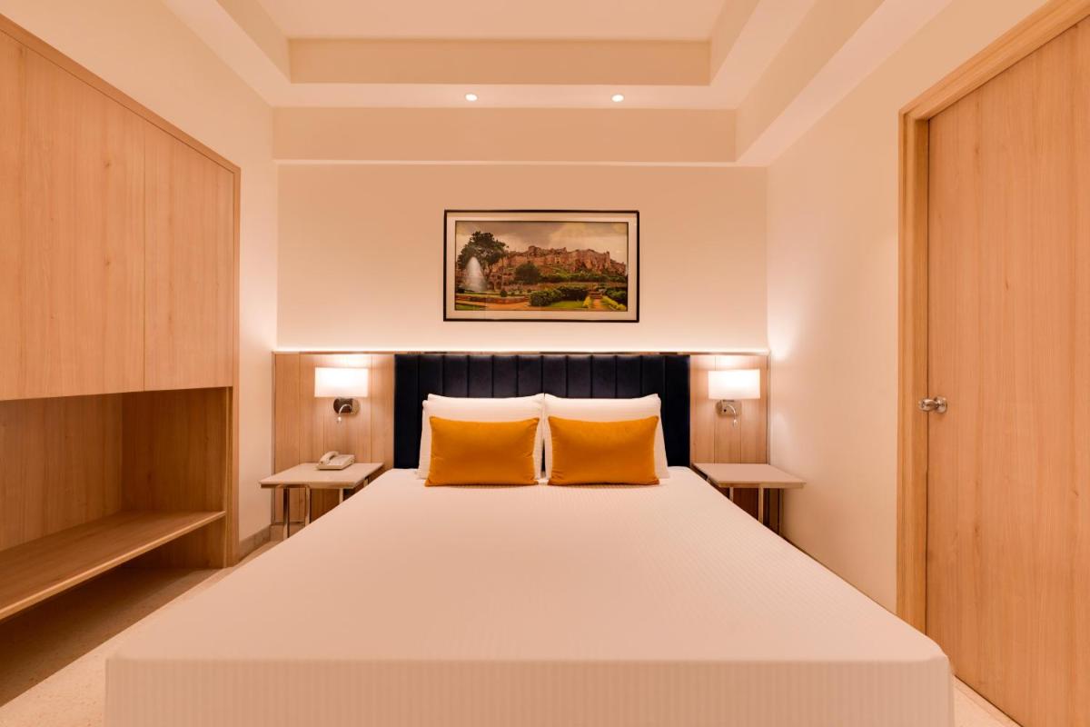 a bedroom with a large bed with two orange pillows at Lemon Tree Premier Hitec City Hyderabad in Hyderabad