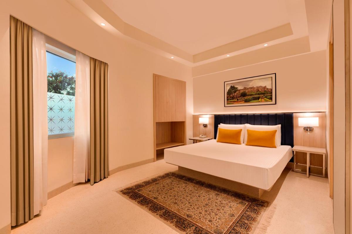 a bedroom with a bed with orange pillows and a window at Lemon Tree Premier Hitec City Hyderabad in Hyderabad