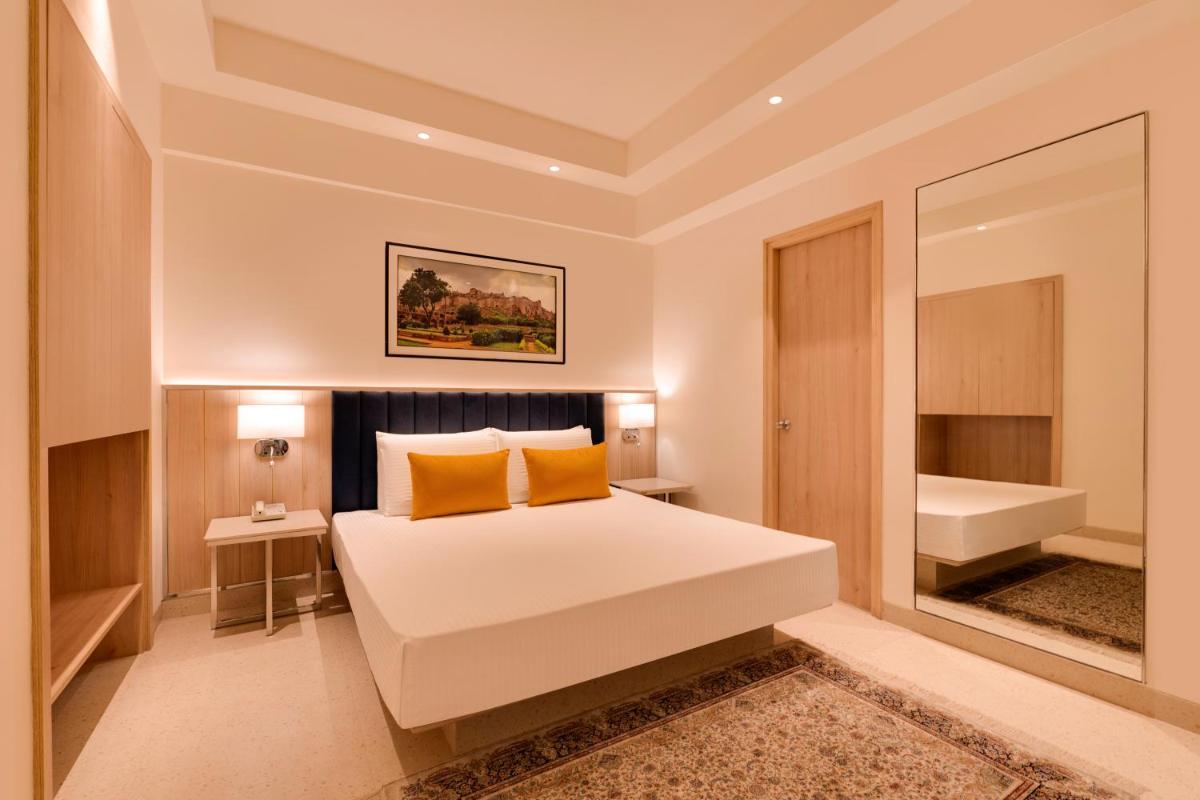 a bedroom with a large white bed with yellow pillows at Lemon Tree Premier Hitec City Hyderabad in Hyderabad
