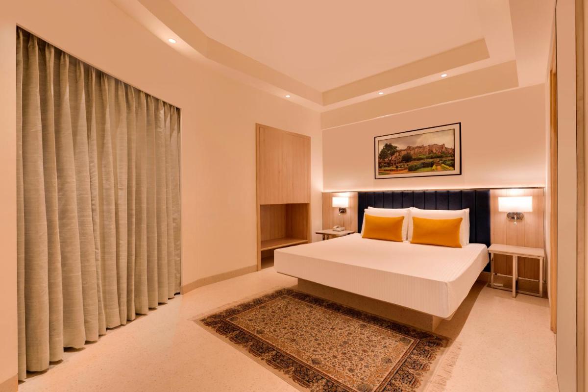a bedroom with a bed with two orange pillows at Lemon Tree Premier Hitec City Hyderabad in Hyderabad