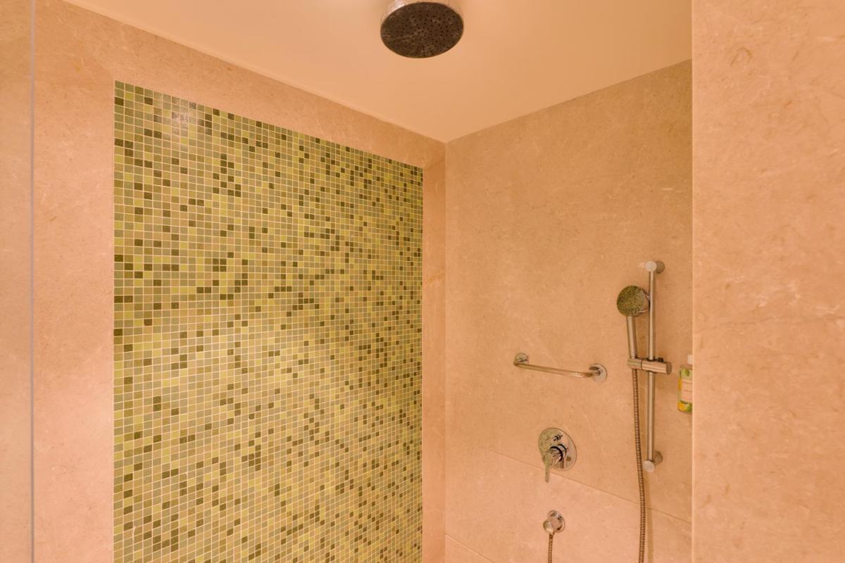 a bathroom with a shower with a tiled wall at Lemon Tree Premier Hitec City Hyderabad in Hyderabad