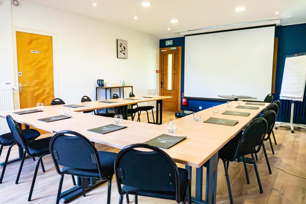 une salle de conférence avec des tables et des chaises et un tableau blanc dans l'établissement Hôtel Spa & Restaurant Ô Pervenches, à Chambéry