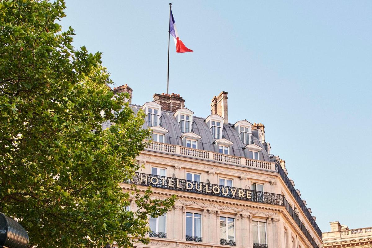 un bâtiment avec un drapeau en haut dans l'établissement Hôtel du Louvre, in The Unbound Collection by Hyatt, à Paris