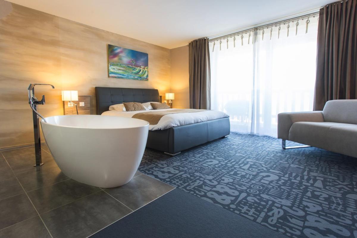 une chambre d'hôtel avec baignoire et lit et lit dans l'établissement Hôtel Le Dormeur, à Dorlisheim