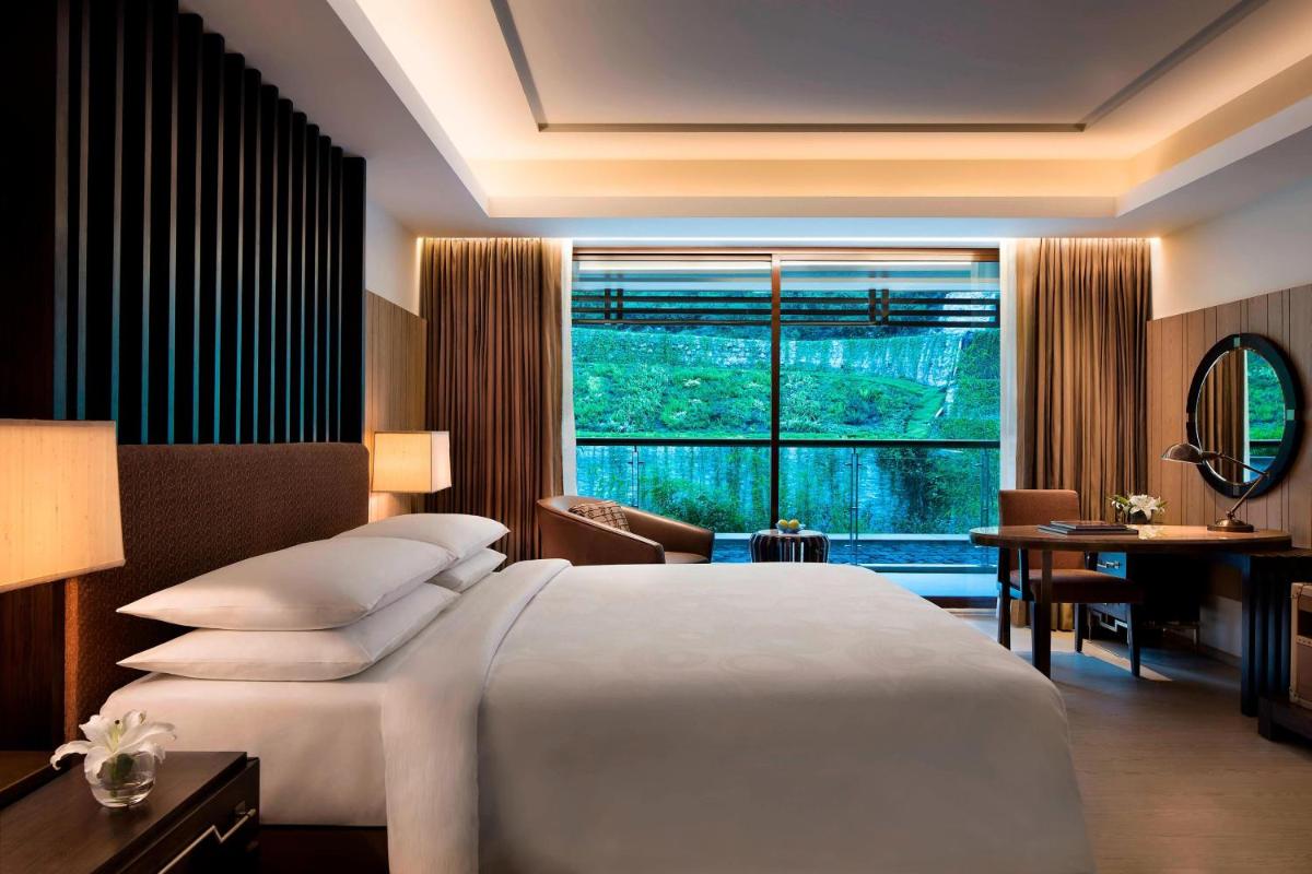 a bedroom with a large bed and a large window at JW Marriott Mussoorie Walnut Grove Resort & Spa in Mussoorie