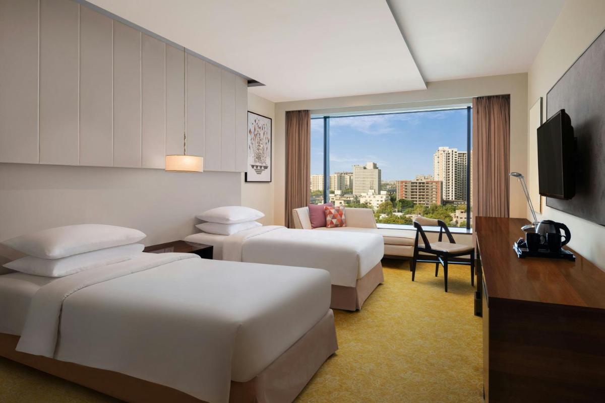 a hotel room with two beds and a window at Renaissance Ahmedabad Hotel in Ahmedabad