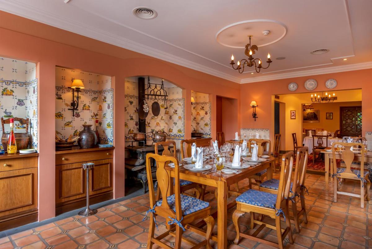 uma sala de jantar com mesa e cadeiras de madeira em Pestana Quinta Perestrello no Funchal