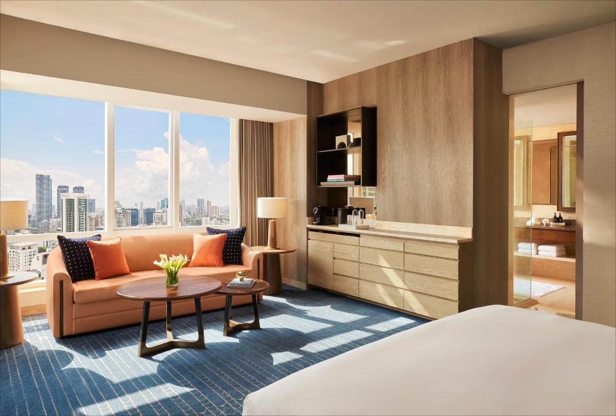 a hotel room with a bed and a couch and a table at Four Seasons Hotel Mumbai in Mumbai
